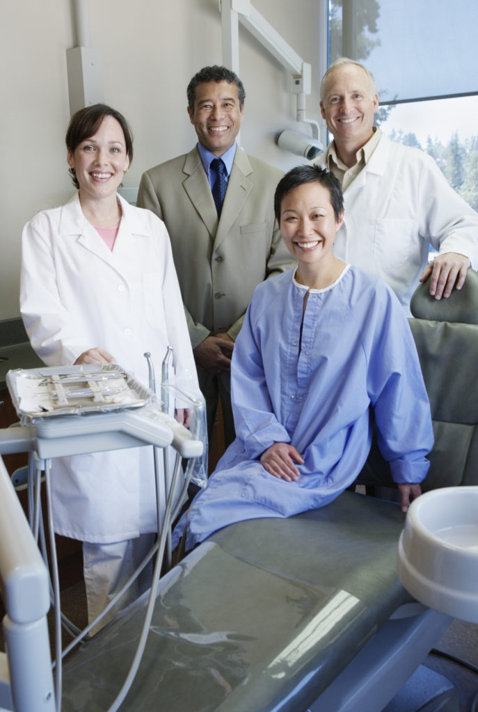 Two dentists, dental assistant and businessman in exam room, portrait