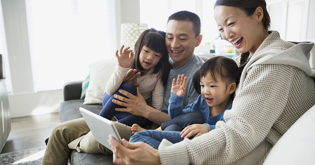 Family waving on digital tablet video conference